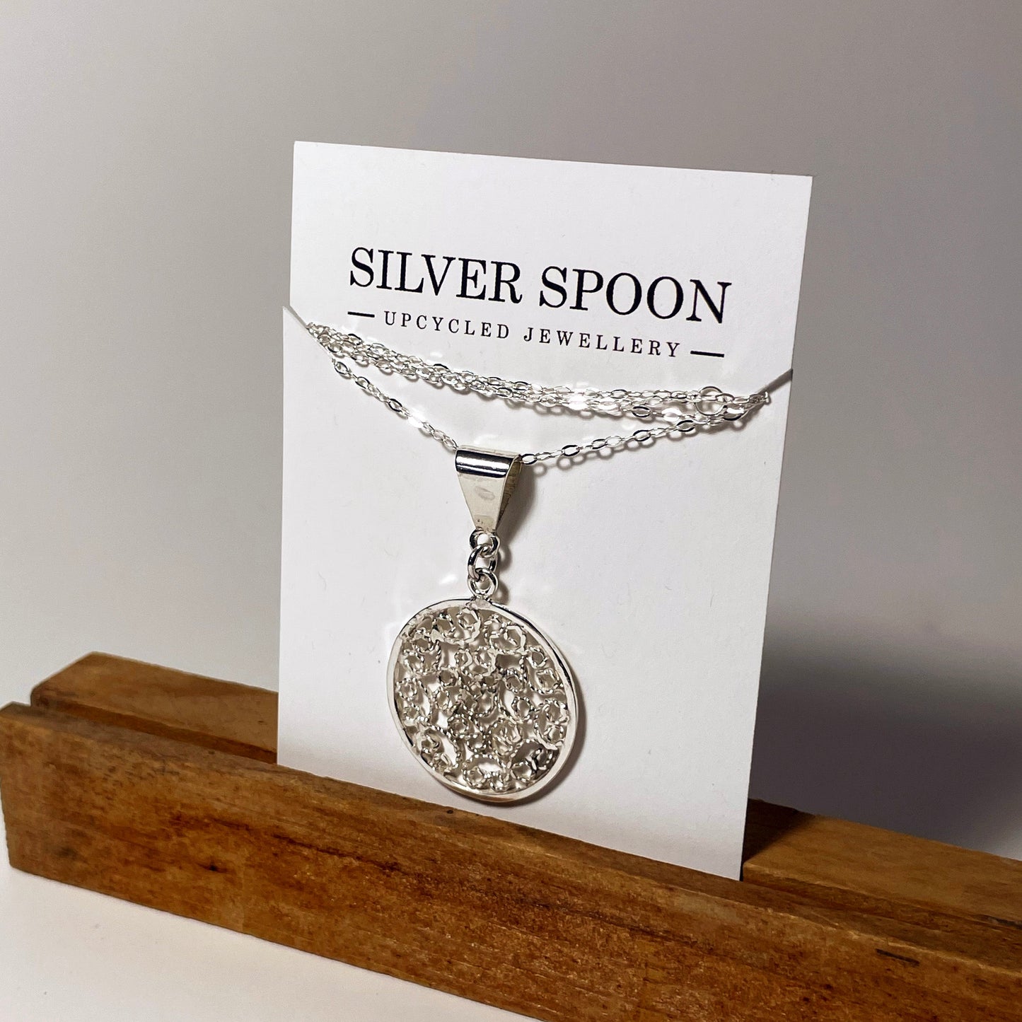 A silver filigree necklace displayed on a card, with the brand name 'Silver Spoon' visible.
