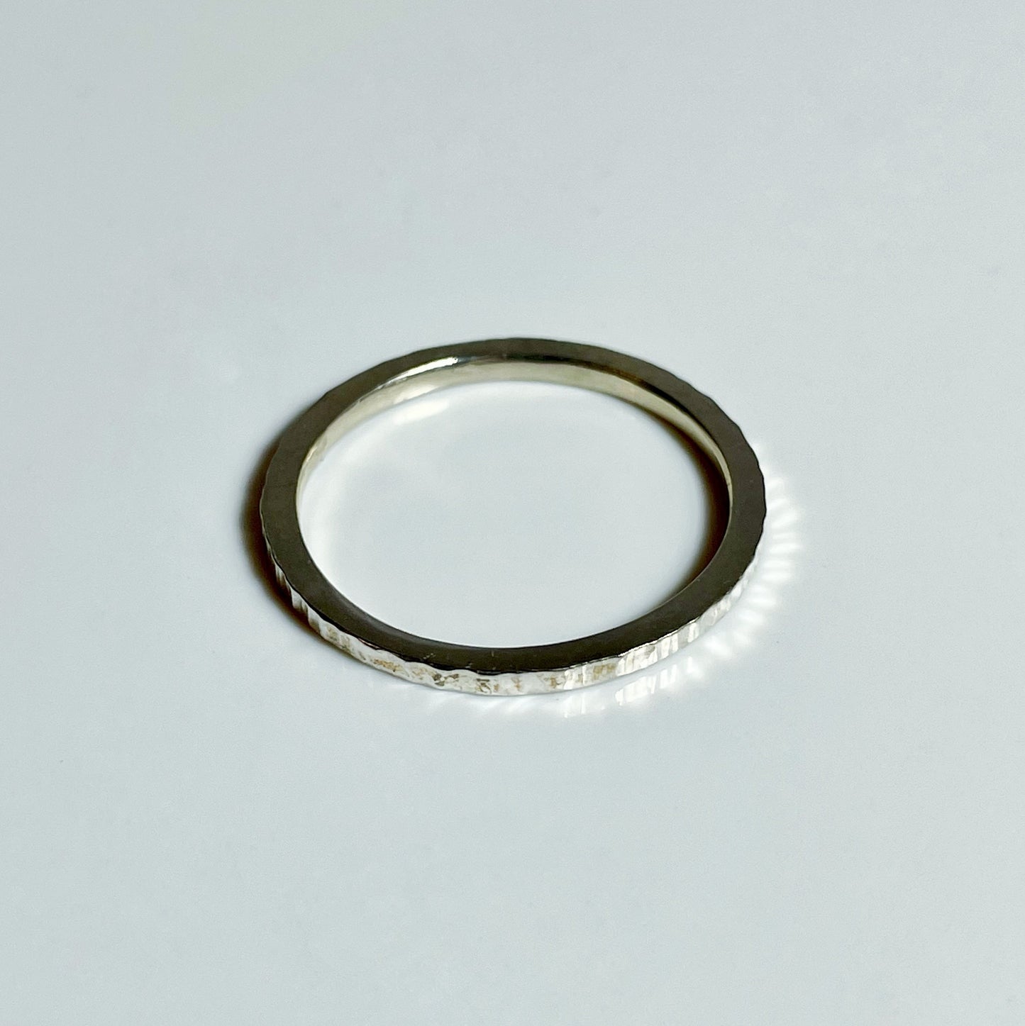 A silver hammered texture stacking ring on a white background.