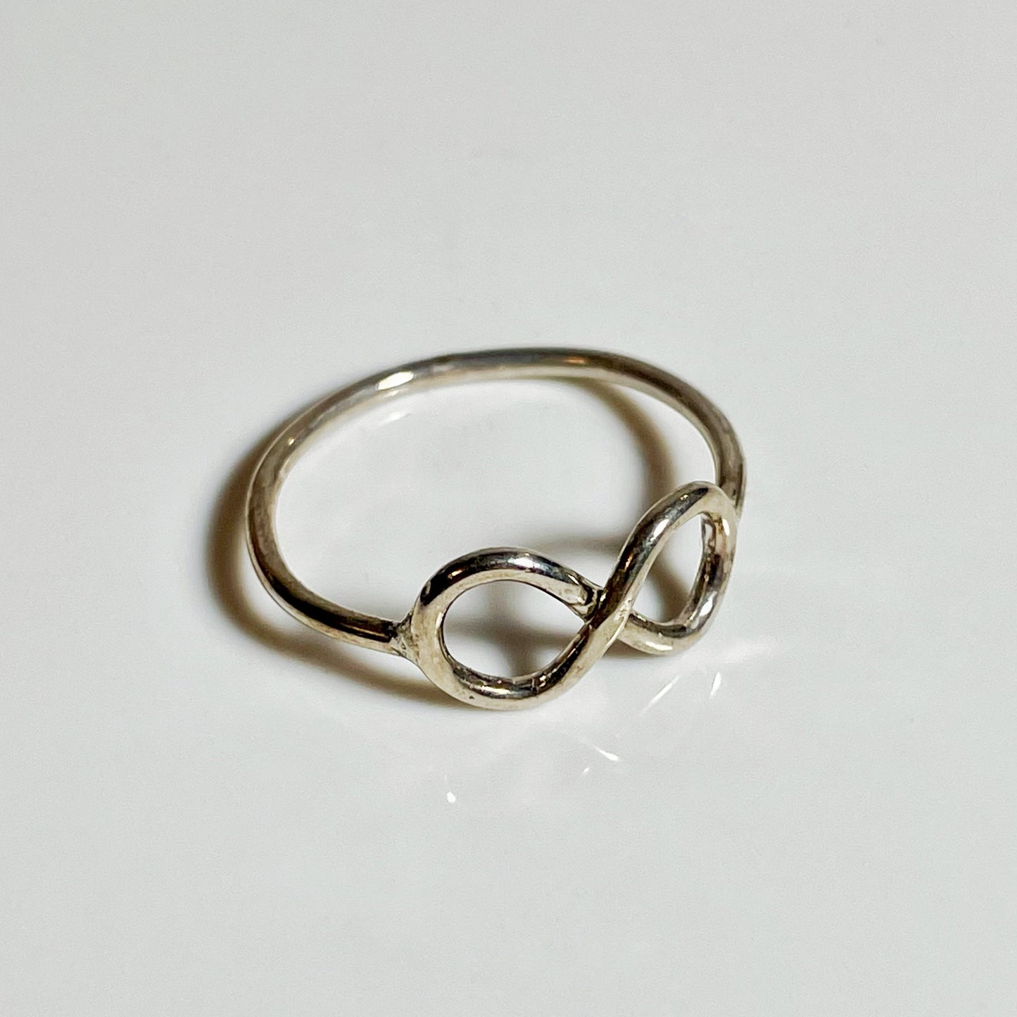 A silver sterling silver infinity stacker ring on a white background.