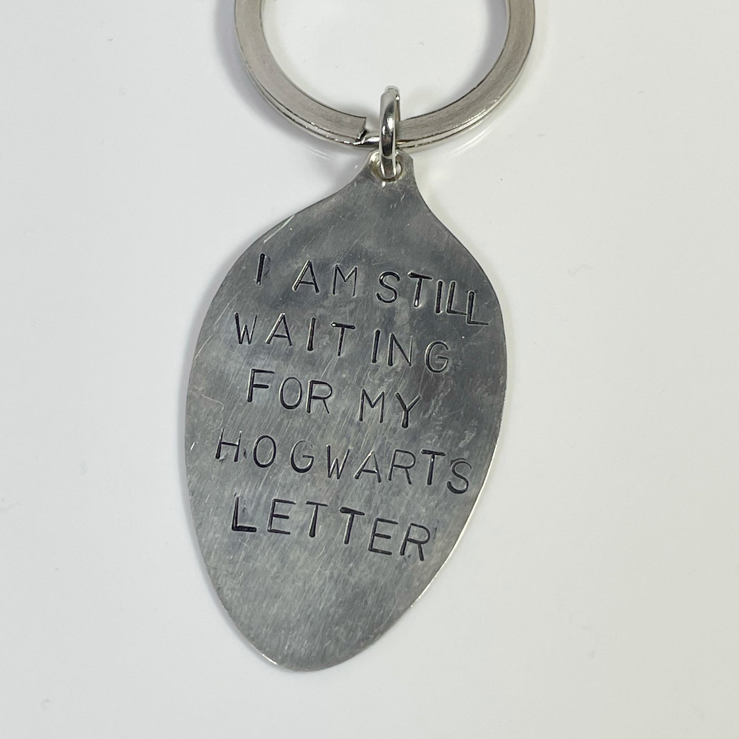 A silver-colored keychain with the text 'I am still waiting for my Hogwarts letter' inscribed.