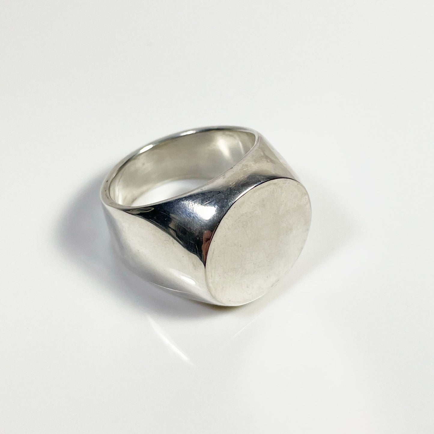 A polished silver signet ring with a simple design on a white background.