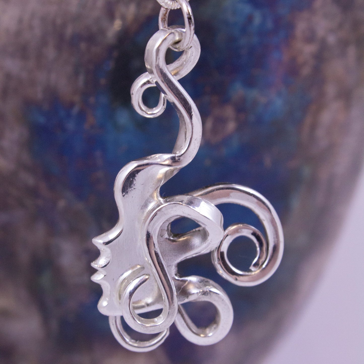 A shape of a woman's face cut out of a for with the fork tines twisted in coils for hair.