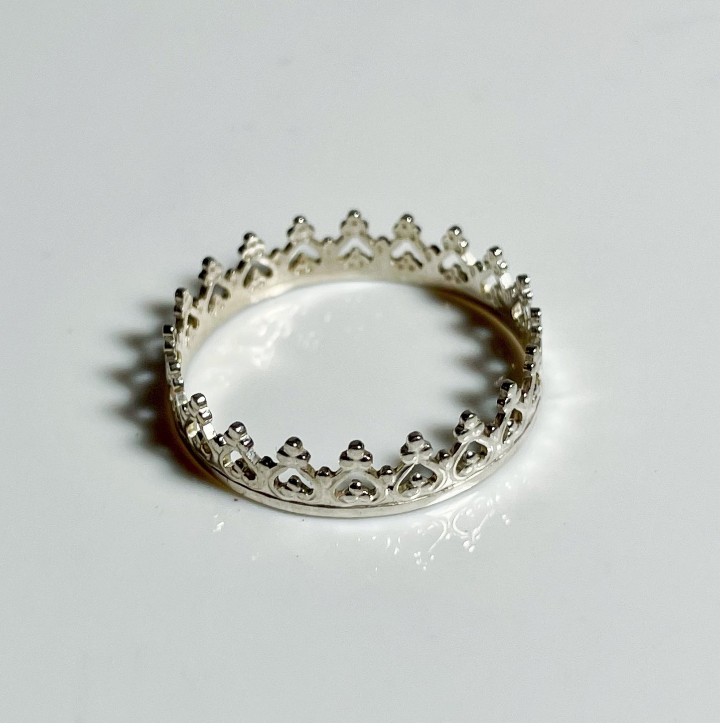 A sterling silver bezel wire ring with a textured band and a small crown-like design at the top.