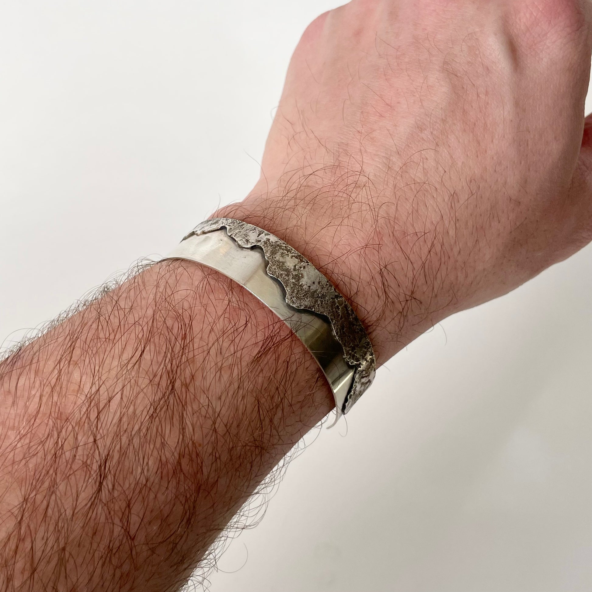 Silver bracelet on a person's wrist against a plain background