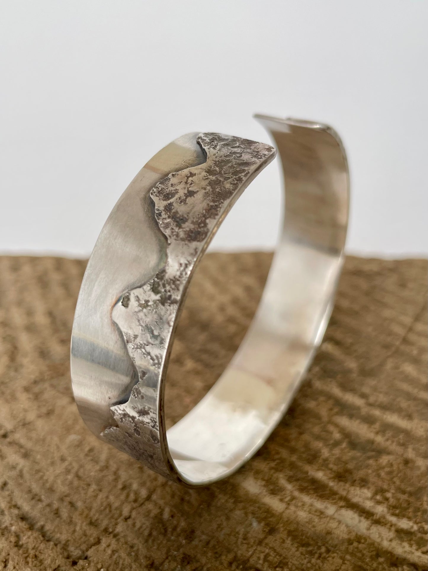 Silver bracelet on a textured surface with a neutral background