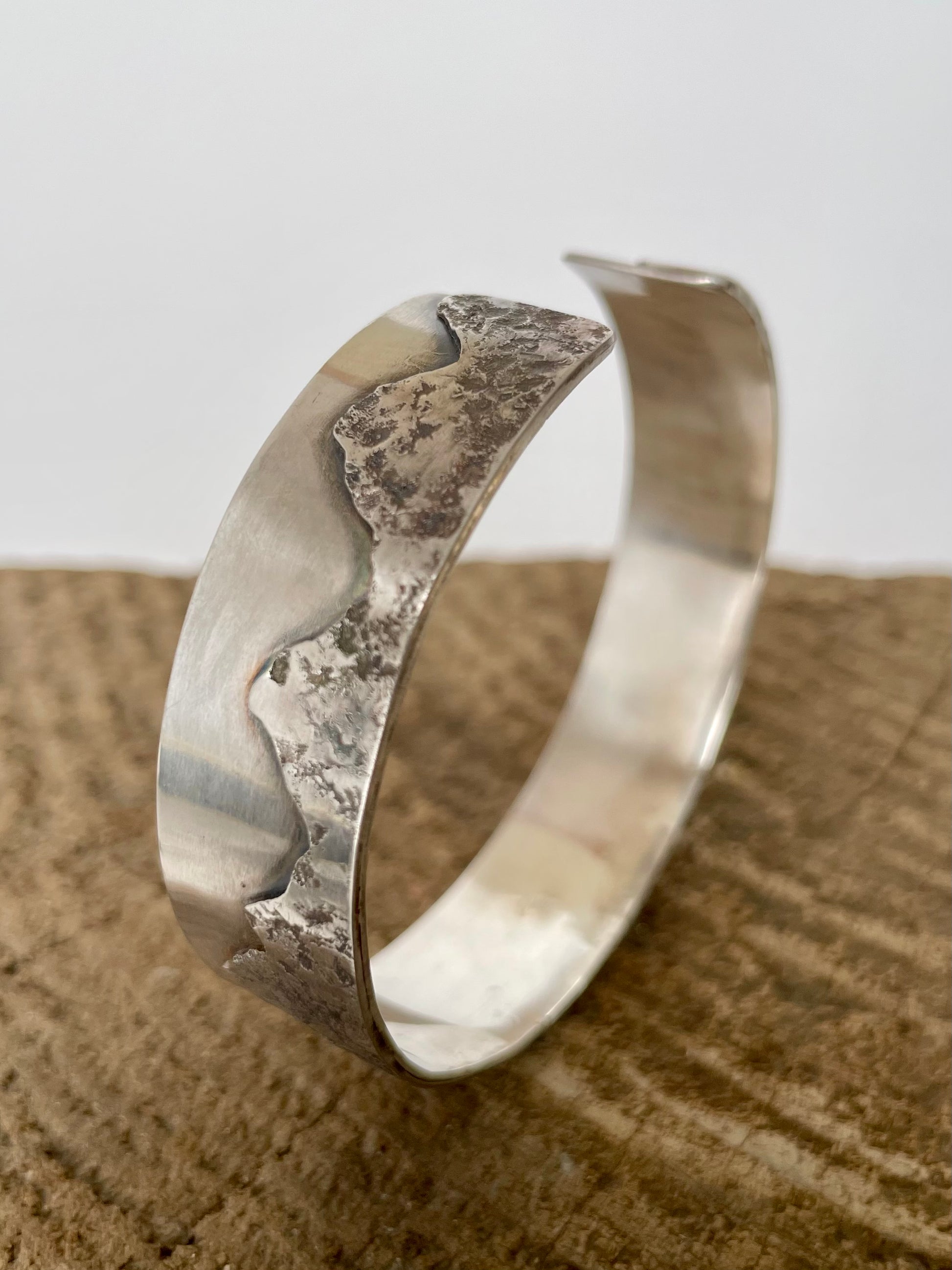Silver bracelet on a textured surface with a neutral background