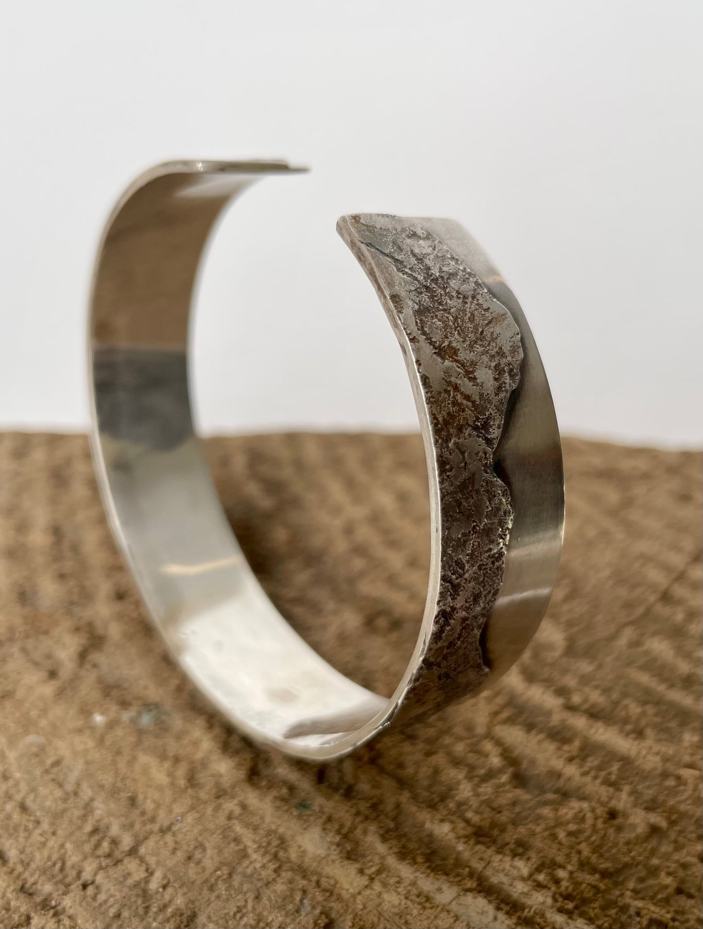 Silver bracelet on a textured surface with a neutral background