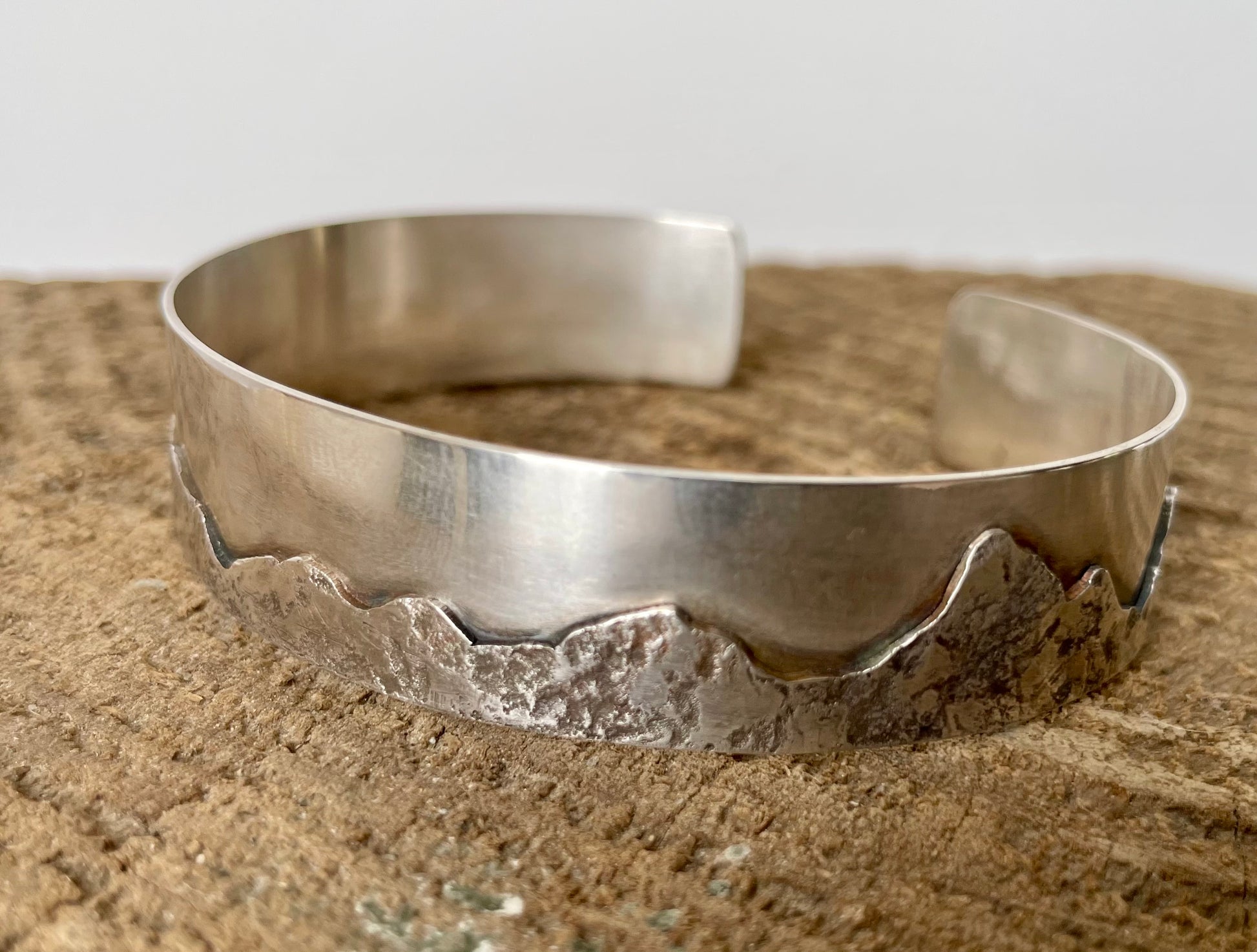 Silver bracelet on a textured surface with a neutral background