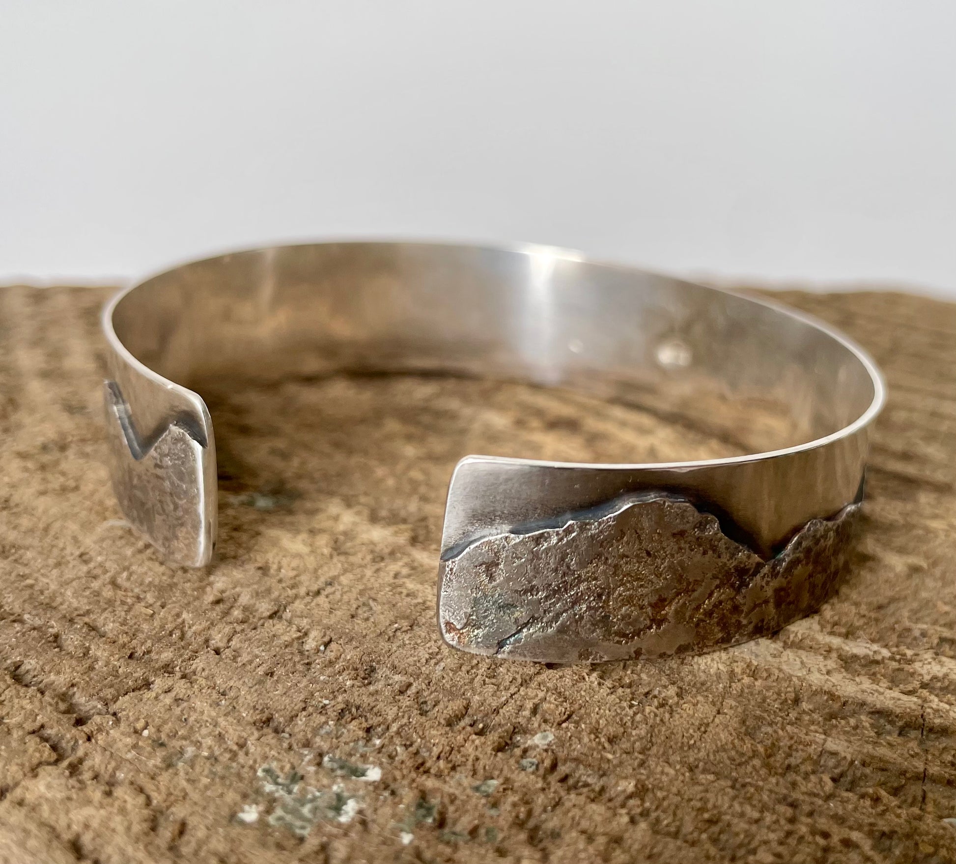 Silver bracelet on a textured surface with a neutral background